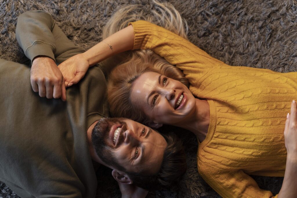 couple allongé sur un tapis, grands sourire , ils ont l'air très heureux d'être ensemble, représente l'étape de l'engagement durable dans un couple couple allongé sur un tapis, grands sourire , ils ont l'air très heureux d'être ensemble